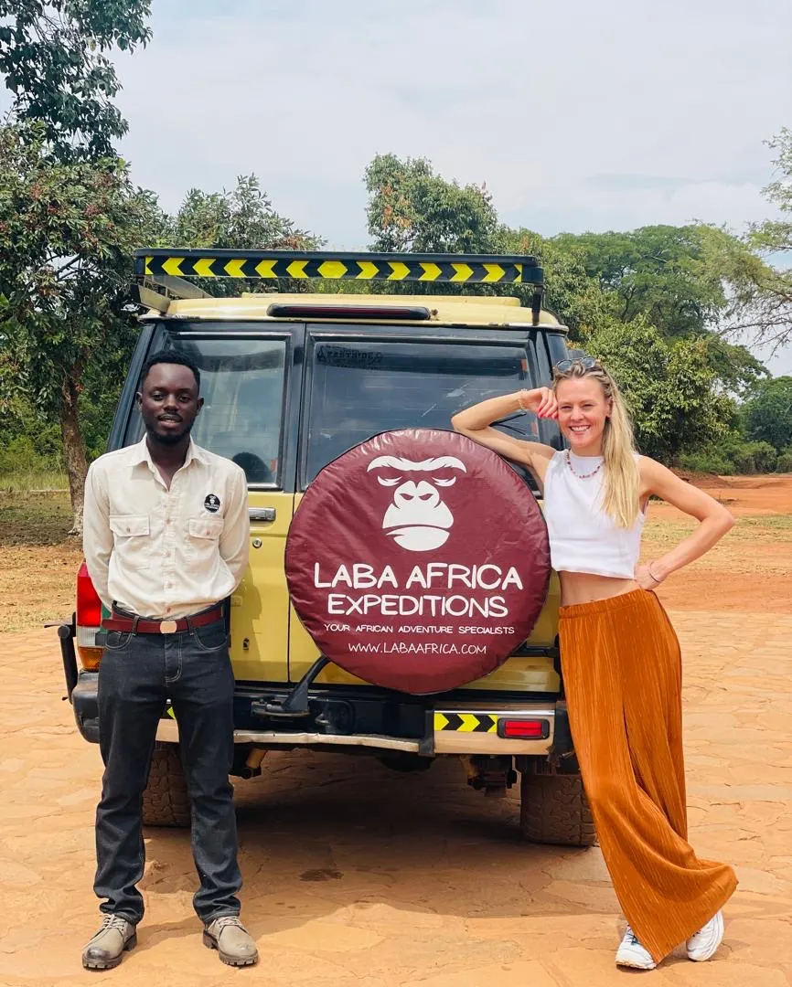 Chauffeur-guide Laba Africa et voyageuse devant un véhicule 4x4