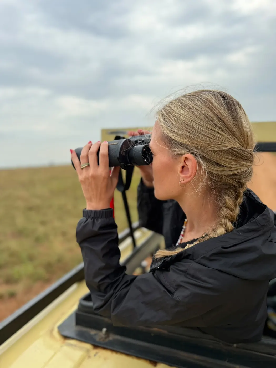 Voyageuse observant la faune aux jumelles pendant un safari en Ouganda